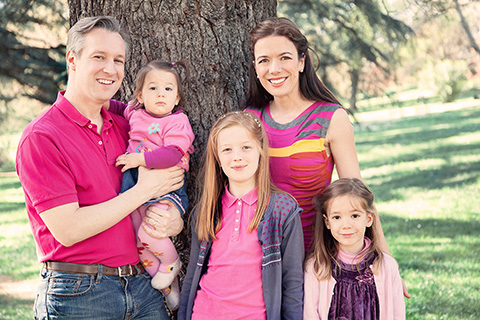 Familia compuesta por padres y tres hijas, posan en un reportaje familiar en exteriores, están en el Parque del Oeste y visten en tonos rosas y fucsias.