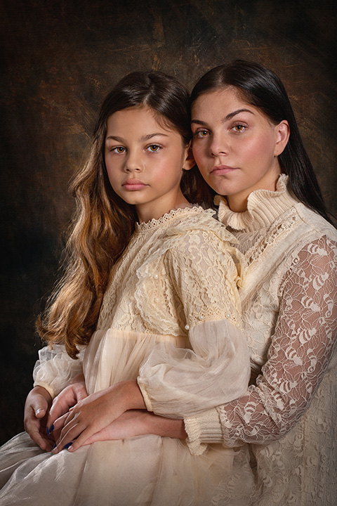 Madre e hija sentada una sobre la otra, llevan un vestido beige de encaje, imagen realizada por fotógrafos de familia en estudio.